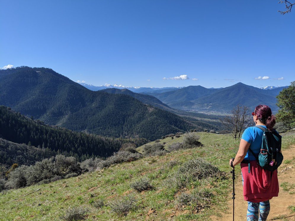 East Applegate Ridge Trail Woman standing on a trail with mountain views.